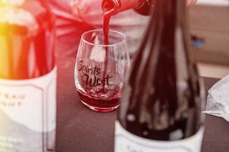 Red wine being poured into a branded Spirits of the West tasting glass